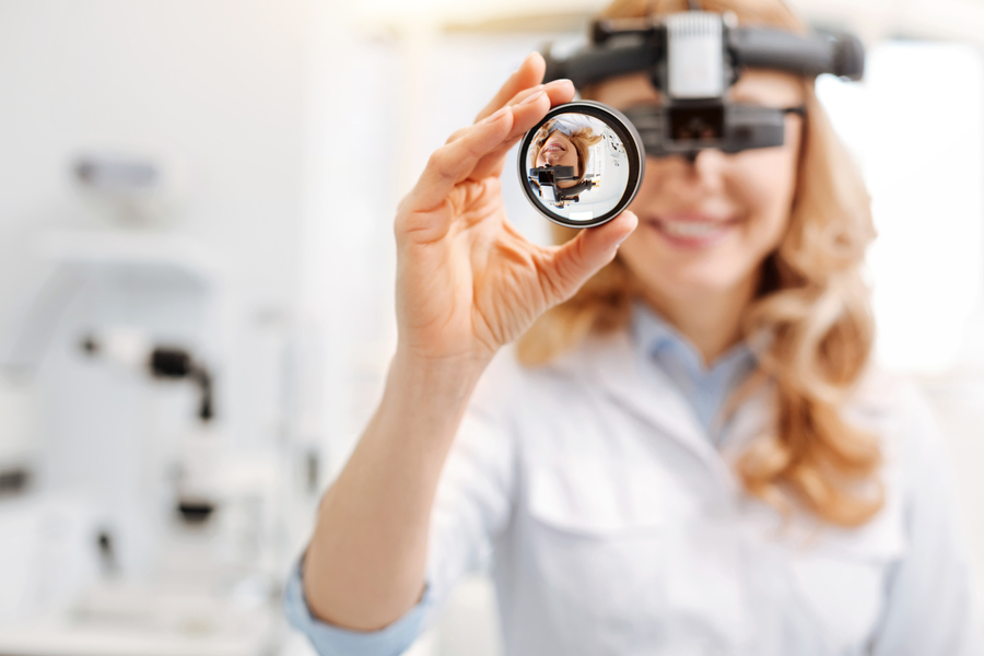 Especialista em retina mostrando os aparelhos e a lente de exame